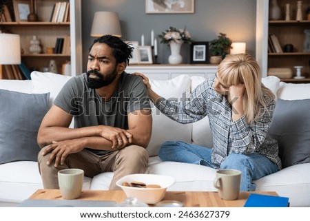 Communication problems, relationship difficulties. Young couple man and woman sitting on sofa at home, argue and misunderstanding. Two angry and sad people having issue with ego and guilt.