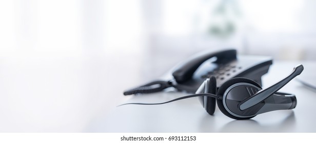 Коммуникационная поддержка, колл-центр и служба поддержки клиентов. VOIP гарнитура на клавиатуре ноутбука.