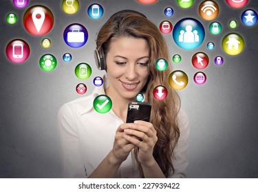 communication technology mobile high tech concept. Young woman using texting listening to music on smartphone with social media application symbols icons flying out of screen isolated grey background.