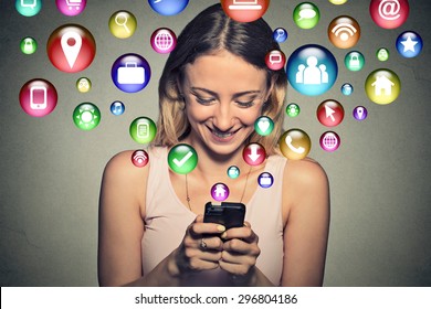 communication technology mobile high tech concept. Closeup happy young woman using texting on smartphone with social media application symbols icons flying out of screen isolated on grey background.