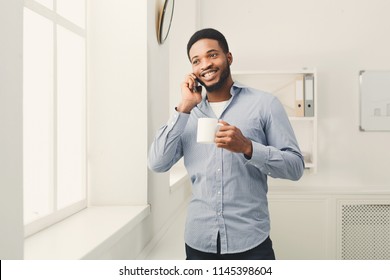 Communication, technology, success. African-american businessman talking on phone near window at office workplace, copy space - Powered by Shutterstock