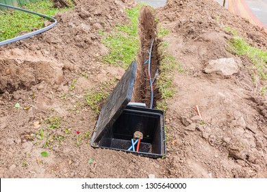 Communications new internet fast speed fiber optic cables been installed underground in dug trenches along road front of residential homes .