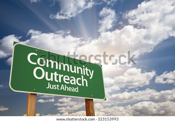 Community Outreach Green Road Sign With Dramatic\
Clouds and Sky.