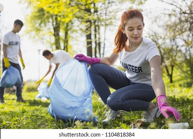 Community project. Beautiful female volunteer looking down while gathering rubbish