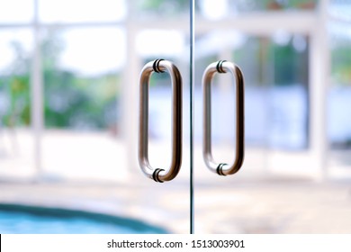 Community Recreation Center, Resort, Swimming And Leisure Activities Background. Glass Door, Metal Chrome Handles With Defocused Indoor Swimming Pool. 