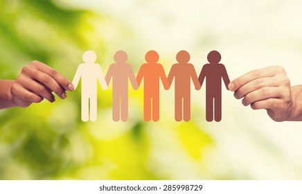 Community, Unity, People And Support Concept - Couple Hands Holding Paper Chain Multiracial People Over Green Background