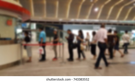 Commuter Getting In Line In The Long Queue For Changing Coin For Buying Train Ticket After Working Day At Station, Thailand. Blurred Background.