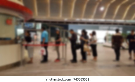 Commuter Getting In Line In The Long Queue For Changing Coin For Buying Train Ticket After Working Day At Station, Thailand. Blurred Background.