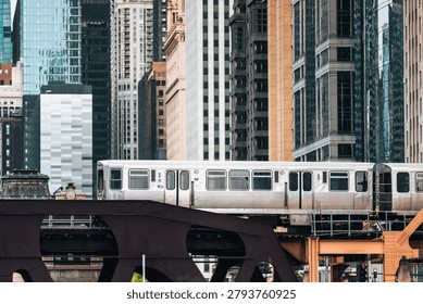Commuter train passing on elevated railway bridge in downtown Chicago city center. Urban transit, transportation infrastructure, metropolitan commute and public travel concept.
