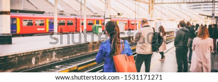 Commuters going to work waiting at train station platform in London city, UK, Europe banner panorama. Train public transport commuting network woman passenger with orange purse panoramic banner.