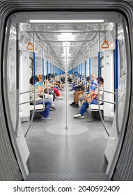 Commuters In Subway Wagon. People Are Sitting In A Modern, Bright Metro Carriage. Symmetry In The Frame. Moscow, RUSSIA, 21.08.2021.