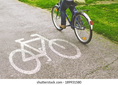 Commuting To Work On A Bicycle. Woman Riding Bicycle On A Bike Path Marked With Symbol.