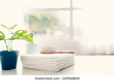 Comp On White Towels And Ceramic Soap, Shampoo Bottles On White Table With Copy Space On Blurred Living Room Background. For Product Display Montage