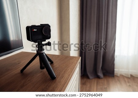 Compact action camera on small tripod in bedroom interior. Concept of home streaming, vlog recording, online content creation, remote communication and modern digital lifestyle.