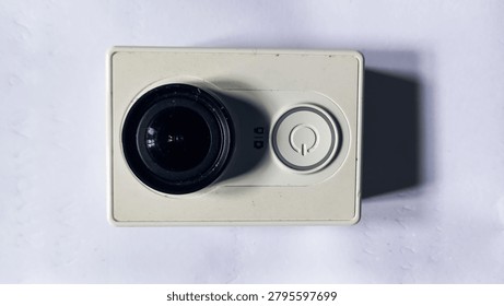Compact action camera with wide-angle lens isolated on white background. Modern gadget for travel, sports, and video recording.