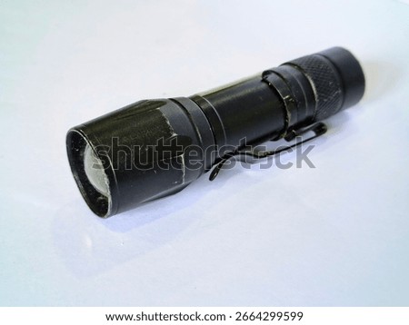 A compact black LED flashlight with a clip, suitable for outdoor activities, emergencies, or everyday carry. A close-up shot on a white background.