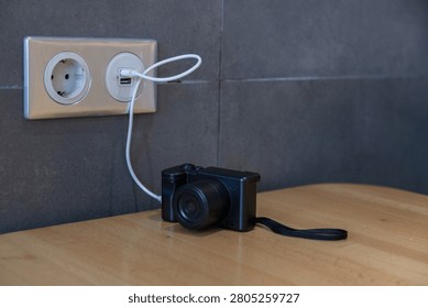 Compact camera charging with USB cable on table. Battery charging and readiness for travel and photography