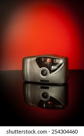 Compact camera photographed on a table in a studio against a red background