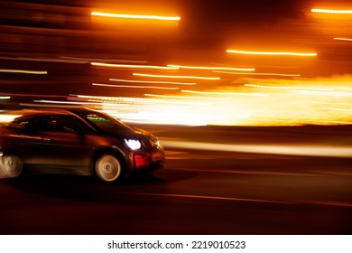 compact car at speed on the street with nighttime light trails