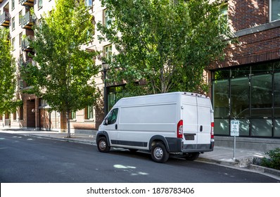 Compact Commercial Cargo Mini Van For Delivery And Small Business Services Standing On The Urban City Street With Multilevel Apartments Buildings