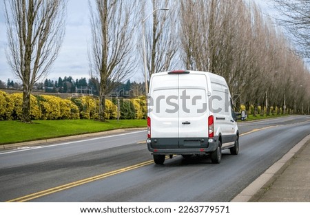 Compact commercial transportation economical, convenient minivan for small business or local moving and delivery of goods driving on the straight local road with trees alley