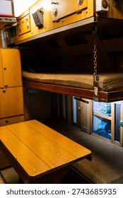 Compact crew sleeping cabin with bunk beds inside historic submarine. Naval vessel interior showing confined living space and military lifestyle.