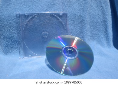 Compact Disc By A CD Case With Blue Background