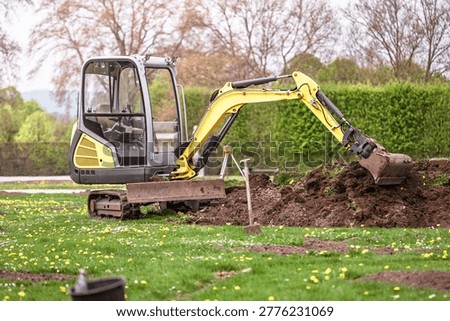 Compact excavator working in garden yard landscaping and ground preparation