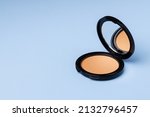 Compact face powder on blue background front view