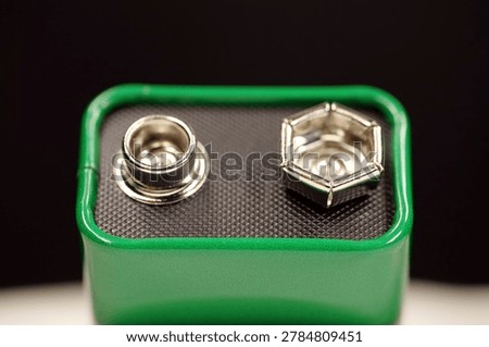 Compact green 9-volt battery isolated, electric battery with terminals supplying nominal 9 volts and ready for use in electronic devices