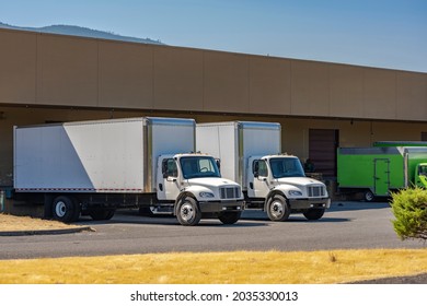 Compact Industrial Medium Size Rigs Day Cab Semi Trucks With Long Box Trailers For Local Delivery And Small Business Needs Standing At Warehouse Dock Loading Commercial Cargo For The Next Freight