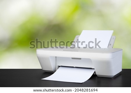 Compact laser printer on black desk against blurred background