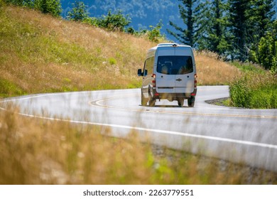 Compact luxury commercial transportation economical, convenient minivan for small business or local moving and delivery of goods running on the winding road with hills on the sides