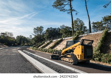 Compact mini loader or tracked loader on a road construction site in the middle of a pine forest