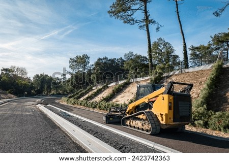 Compact mini loader or tracked loader on a road construction site in the middle of a pine forest