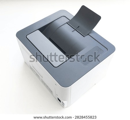A compact modern laser printer stands on a white surface