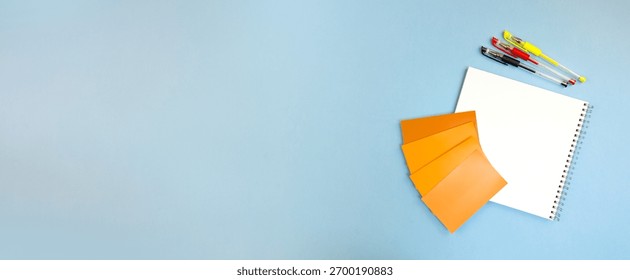compact notebook with scattered pens and orange swatches at corner, casual onthe-go sketching setup, spontaneous note taking and color testing for creative professionals or students