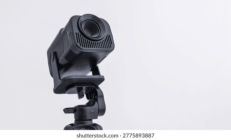 A compact, portable digital projector is positioned on a sturdy tripod, ready for use in various settings