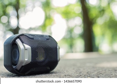 Compact Portable Speaker With Detailed Geometric Forms Shapes Placed On Rough Surface With Copy Space – Movable Wireless Gadget For Playing Music Outdoor With Blurred Background