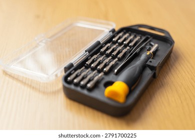 Compact precision screwdriver bit kit with clear lid and yellow handle for electronics repair and diy toolkit background for banner or poster design.