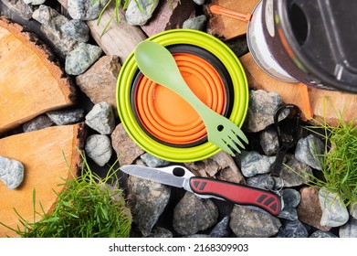 Compact silicone utensils. Compact travel utensils. Travel utensils and an army knife on stones. View from above.