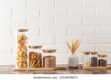 Compact, stylish storage of bulk products in glass jars with bamboo lids. front view. White brick wall. kitchen background - Powered by Shutterstock