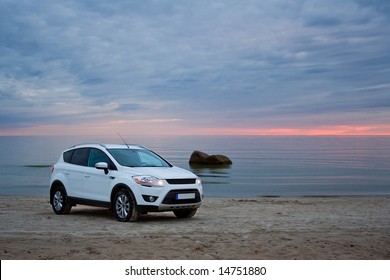 A Compact SUV On A Beach. Sunset.