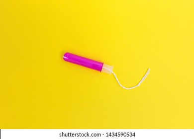 Compact Tampon With Pink Plastic Applicator For Women Period. Yellow Background