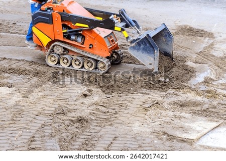 Compact track loader is used to move level soil at construction site during works day