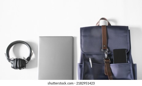 A Compact Urban Backpack For A Laptop With A Smartphone And A Fountain Pen Lies On A White Table Next To A Laptop And Headphones. Study, Travel And Lifestyle With Gadgets. Copy Space. Close-up