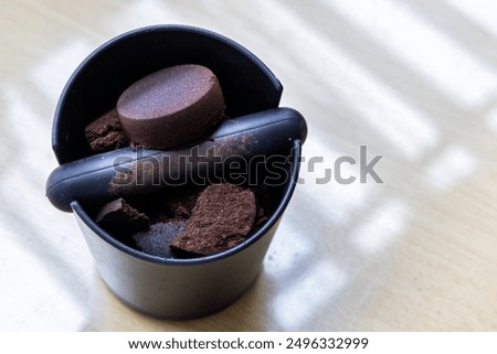 Compacted coffee ground in knock box on table. Coffee grounds are excellent natural fertilizers.