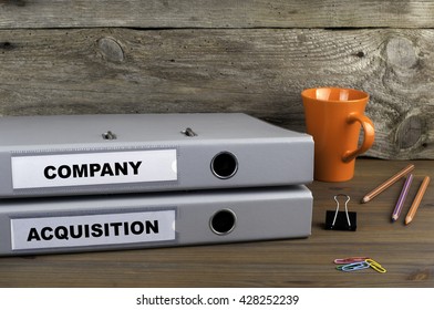 Company And Acquisition - Two Folders On Wooden Office Desk