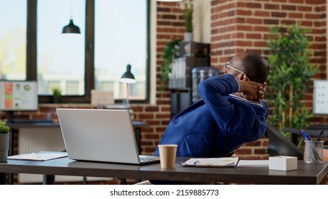 Company assistant relaxing on work timeout in startup office, relieving stress for peace of mind. Sitting with hands behind head, laid back on chair enjoying break pause at desk.