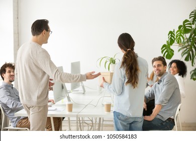 Company Boss Introducing New Employee To Colleagues, Executive And Friendly Team Welcoming Greeting Hired Woman Newcomer Member Holding Box With Belongings On First Day At Work In Office, Rear View